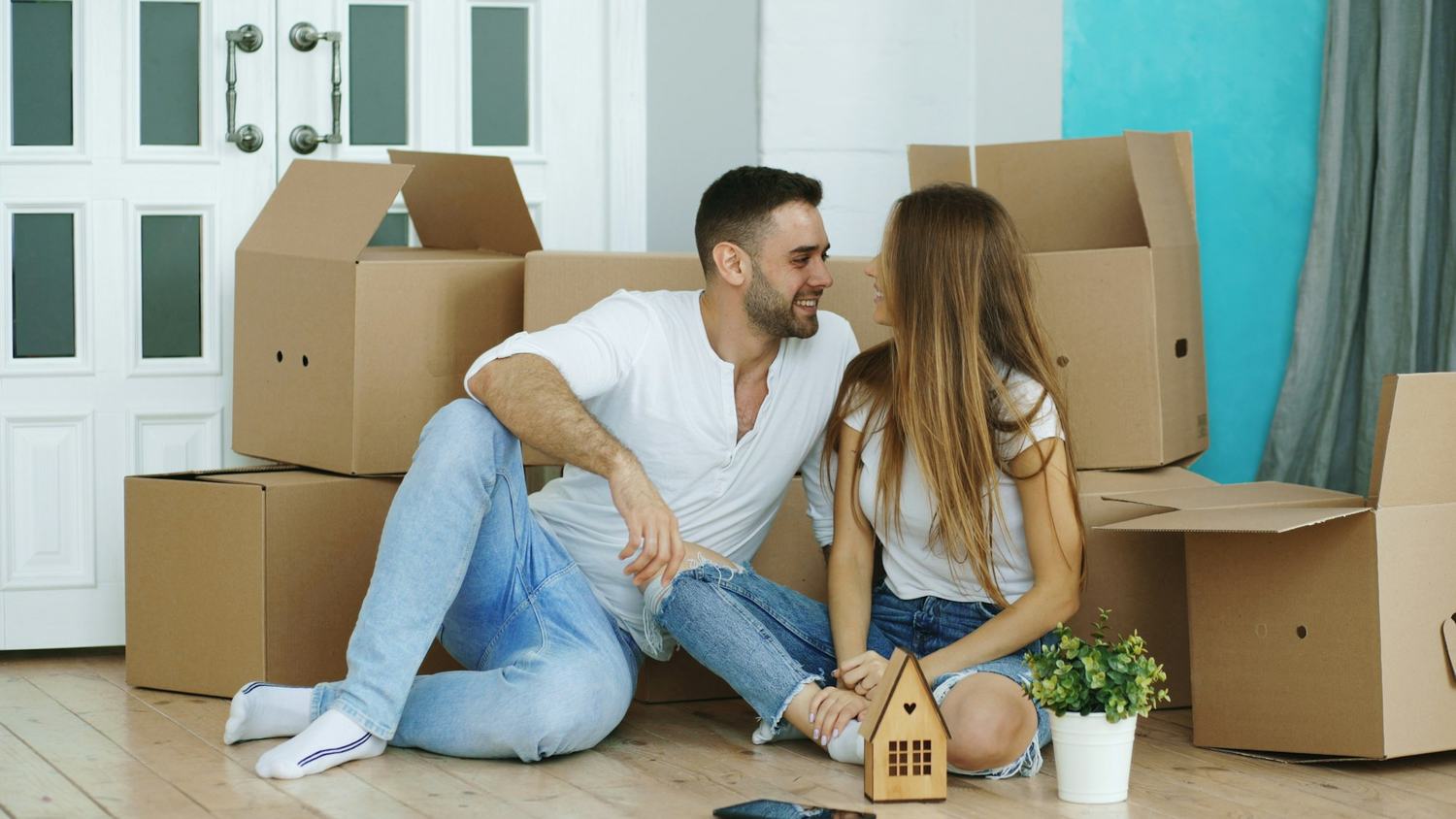 A couple sitting among moving boxes in their new home