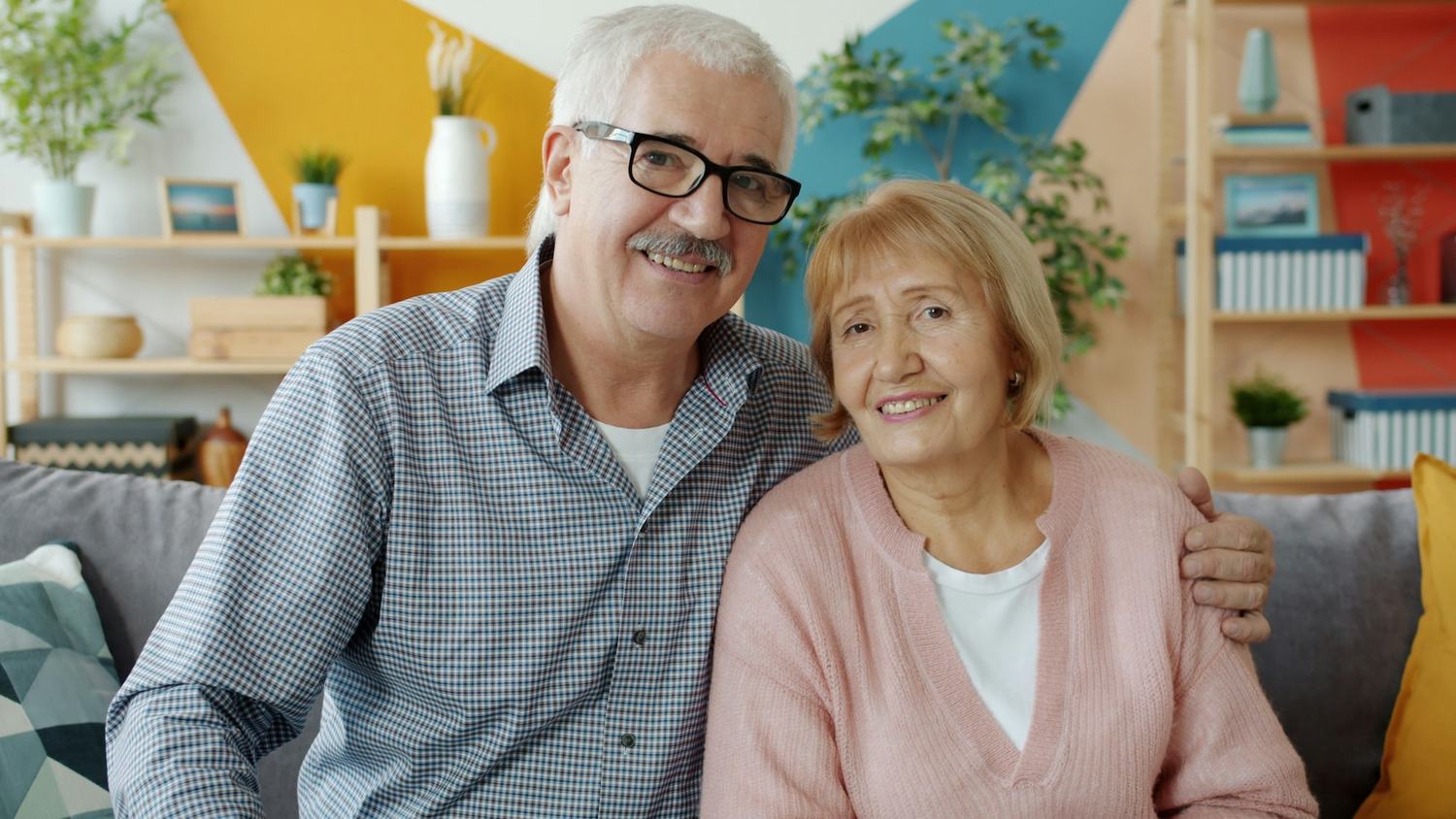 An older couple smiling together on a sofa at home